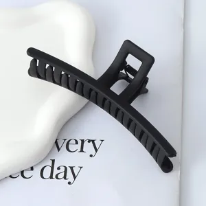 Vista dettagliata di una grande molletta per capelli nera opaca dal design elegante.