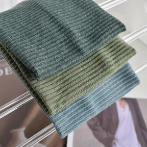 Detailed shot of three ribbed knit headbands in dark green, olive green, and blue-gray.