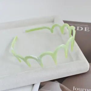 Diadema de pelo ondulada verde claro en detalle, elegante accesorio de acetato para estilo diario.