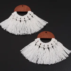 Gros plan détaillé de boucles d'oreilles bohèmes en bois et coton faites à la main.