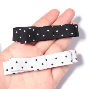 Detalle de horquilla con lazo de lunares en cinta de satén blanco y negro para accesorios DIY.