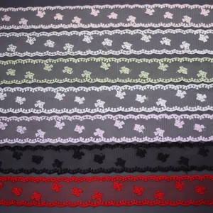 Detailansicht von bunten Polyester-Netzspitzenbändern mit filigraner Schleifen-Bestickung.