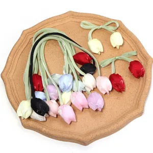 Vue détaillée de bourgeons de tulipes en tissu coloré et accessoires de coiffure en ruban.