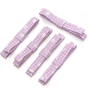 Detail view of purple plaid floral fabric bow DIY accessories for hair clips and doll crafts.