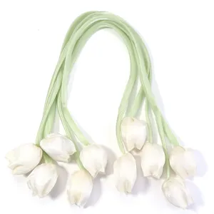 Bourgeons de tulipes en tissu blanc avec rubans verts, détail d'accessoire capillaire.