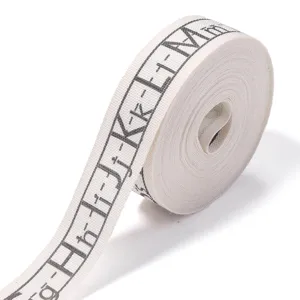 Detailed view of white cotton ribbon roll with alphabet pattern for gift wrapping and crafts.