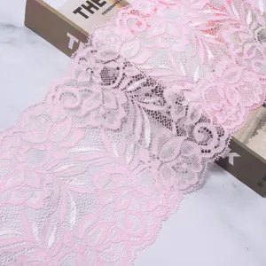 Close-up detail of soft pink stretch lace fabric trim, elegant floral pattern for sewing crafts.