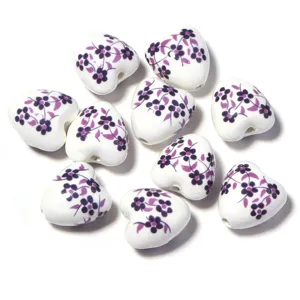 Gros plan détaillé de perles en céramique en forme de cœur avec motif floral pour bijoux.