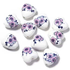 Gros plan de perles en céramique en cœur avec motif floral bleu et rose pour bijoux DIY.