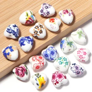 Détail de perles en céramique en forme de cœur imprimées de motifs floraux et de trous de perçage.