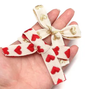 Vista dettagliata di nastri in cotone ricamato con cuori rossi e oro per confezioni regalo.