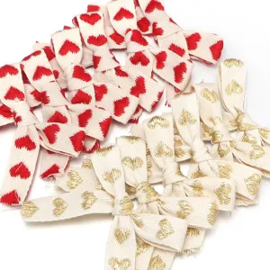 Fiocchi in nastro di cotone con ricamo di cuori rossi e dorati per confezioni regalo.