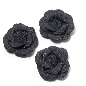 Close-up detail shot of black denim camellia flower, fabric craft DIY accessory for clothing.