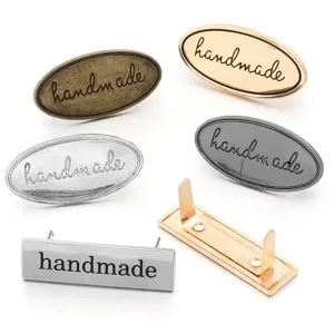 Metal handmade bag label detail showing various metallic finishes and fastener prongs.