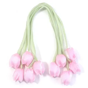 Vue detaillee de fleurs de tulipes en ruban de satin rose faits main avec des tiges vertes.