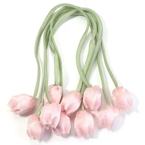 Vue détaillée d'accessoires de fleurs de tulipe en tissu rose, tiges souples pour l'artisanat.