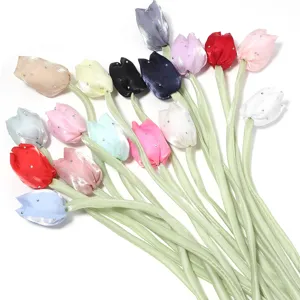 Vue détaillée de beaux boutons de tulipe en tissu coloré avec strass et tiges vertes.