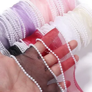 Close-up detail of sheer organza ribbon with elegant pearl beaded edge, perfect for crafts.