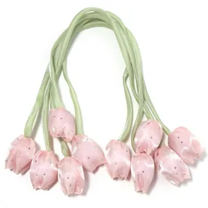 Gros plan détaillé d'accessoires de bourgeons de tulipe en satin rose avec tiges et strass.