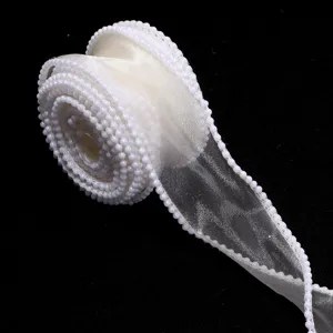 Detailed shot of white organza ribbon roll decorated with delicate small pearls along edges.