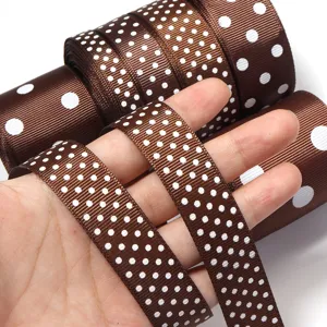 Dettaglio in primo piano di nastro gros-grain marrone con pois bianchi e tessitura fine.