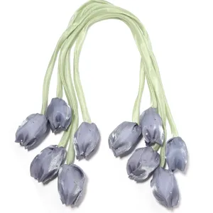 Gros plan de bourgeons de tulipes en tissu avec strass et tiges de ruban vert pour accessoires.