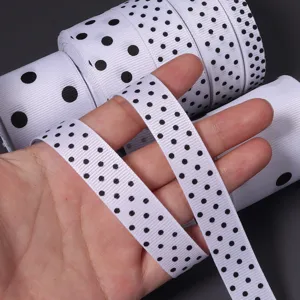 Dettaglio in primo piano di nastro grosgrain bianco a pois neri, ideale per fai da te.