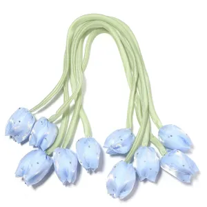 Gros plan détaillé de boutons de fleurs de tulipe en tissu bleu avec strass et rubans.