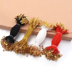Detail view of colorful hang tag strings with safety pins in black, gold, white, and red.