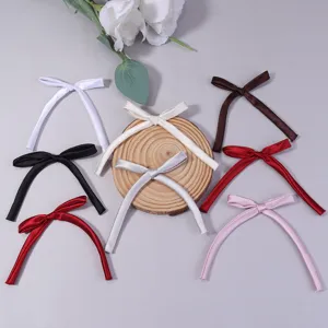 Close-up detail of various colored satin ribbon bows with long tails, ideal for hair clips and gifts.