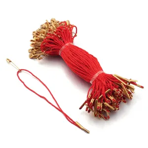 Close up of red hang tag strings with golden metal pins, detail view of garment accessories.