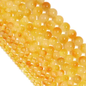 Primo piano di fili di perle rotonde in calcedonio giallo per la creazione di gioielli dettagli.