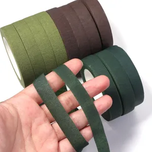 Gros plan détaillé de rouleaux de ruban de masquage floral coloré et ruban papier tenu.