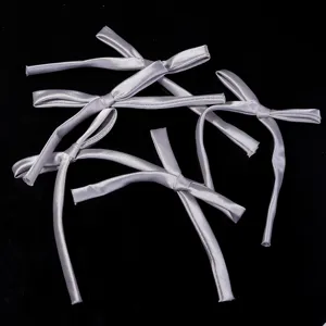Detail shot of silver satin ribbon bows with long tails, ideal for DIY hair clips or gift wrapping.