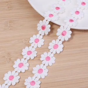 Primer plano de cinta de encaje de margaritas blancas y rosas para accesorios y manualidades.