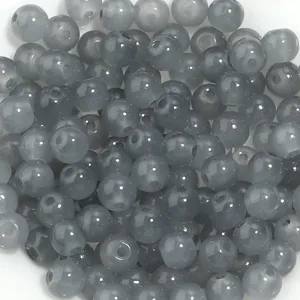 Gros plan détaillé de perles rondes en verre translucide gris pour vos créations de bijoux DIY.