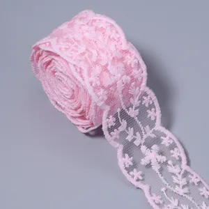 Close-up detail of pink lace trim roll, delicate floral embroidery for DIY craft projects.
