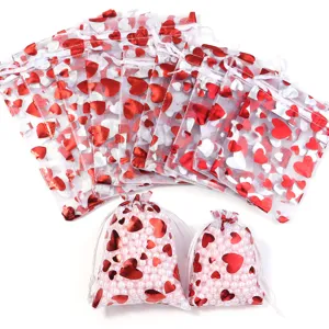 Sacchetti regalo in organza con coulisse e cuori rossi e argentati, ideali per gioielli e dolci di nozze.