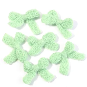 Green knitted bow hair clip accessory DIY craft clothing decorative material close up detail view