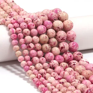 Perline rotonde in pietra maculata rosa, dettaglio per creazione di gioielli fai da te.