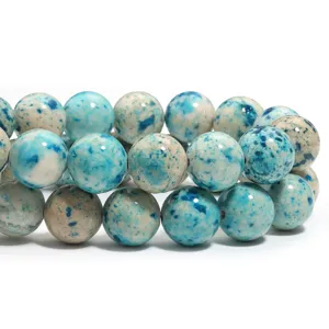 Primo piano dettagliato di perle rotonde in pietra naturale blu e beige, superficie liscia.