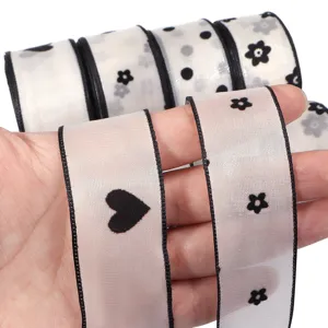 Primo piano di nastro trasparente bianco con floccaggio nero a cuori e motivi floreali.