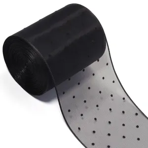 Gros plan détaillé sur le ruban de tulle fin à pois noirs avec une texture délicate.