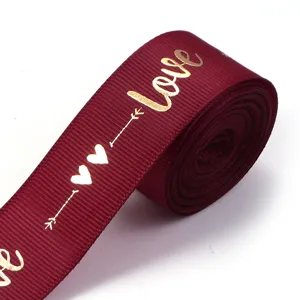 Burgundy polyester ribbon with gold love and heart print, exquisite detail for gift wrapping.