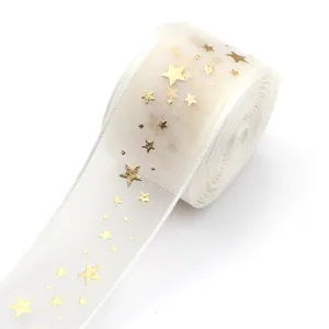 Nahaufnahme eines weißen Organzabandes mit goldenen Sternen, ideal für Geschenkverpackung.
