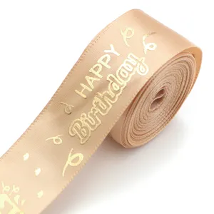 Close-up detail of the champagne gold satin ribbon with metallic birthday stamping pattern.