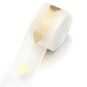 Weisses Organzaband mit metallischen Goldherzen, feine Textur ideal zum Verpacken von Geschenken.