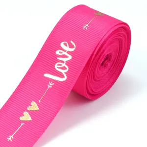 Hot-stamped love ribbon detail, pink polyester fabric with gold hearts for gift wrapping.