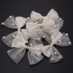 Detail shot of white ribbon bows with mesh tulle and pearl accents for DIY crafts and hair accessories.