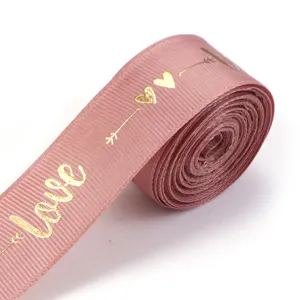 Pink polyester ribbon with gold foil love print, ideal for gift box wrapping and DIY crafts.